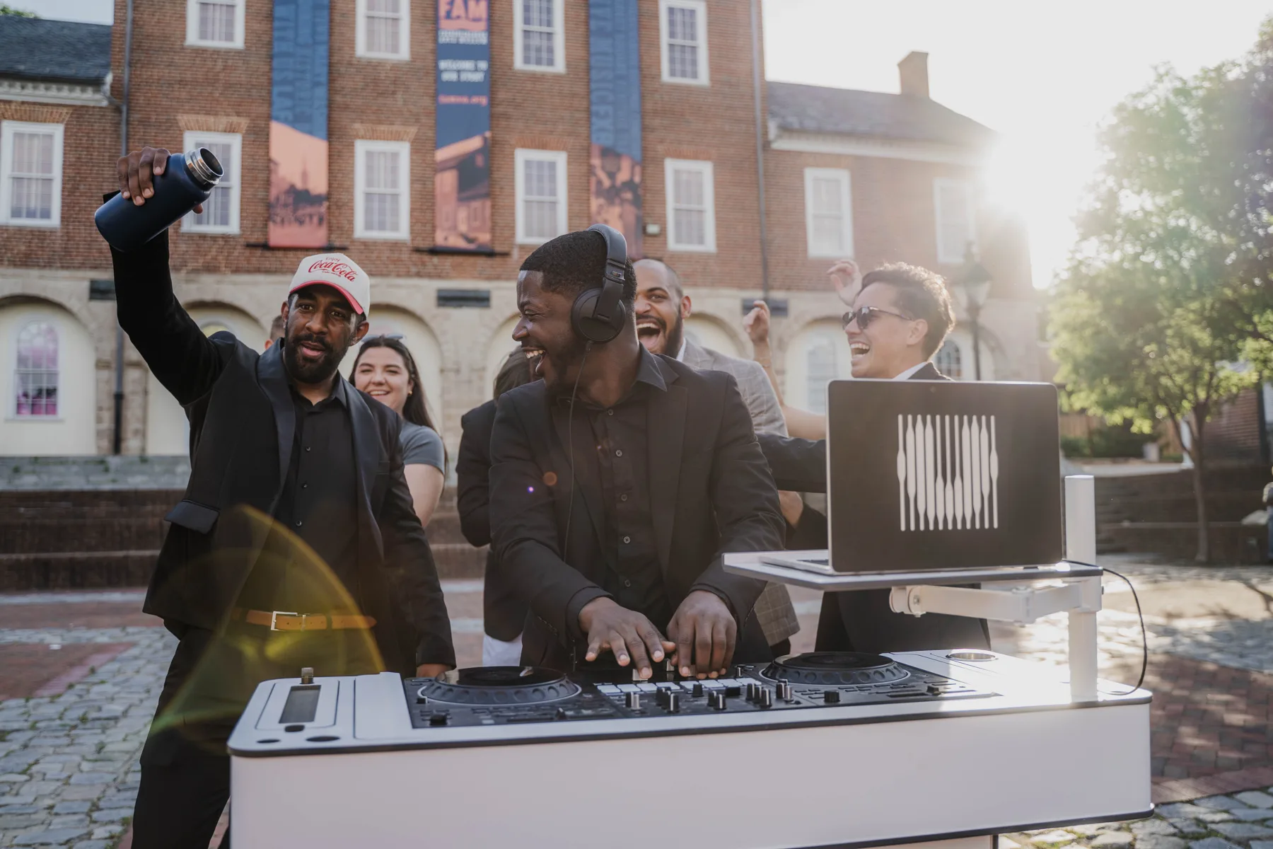 An Upchurch DJ laughing at the decks with the crowd cheering behind him.