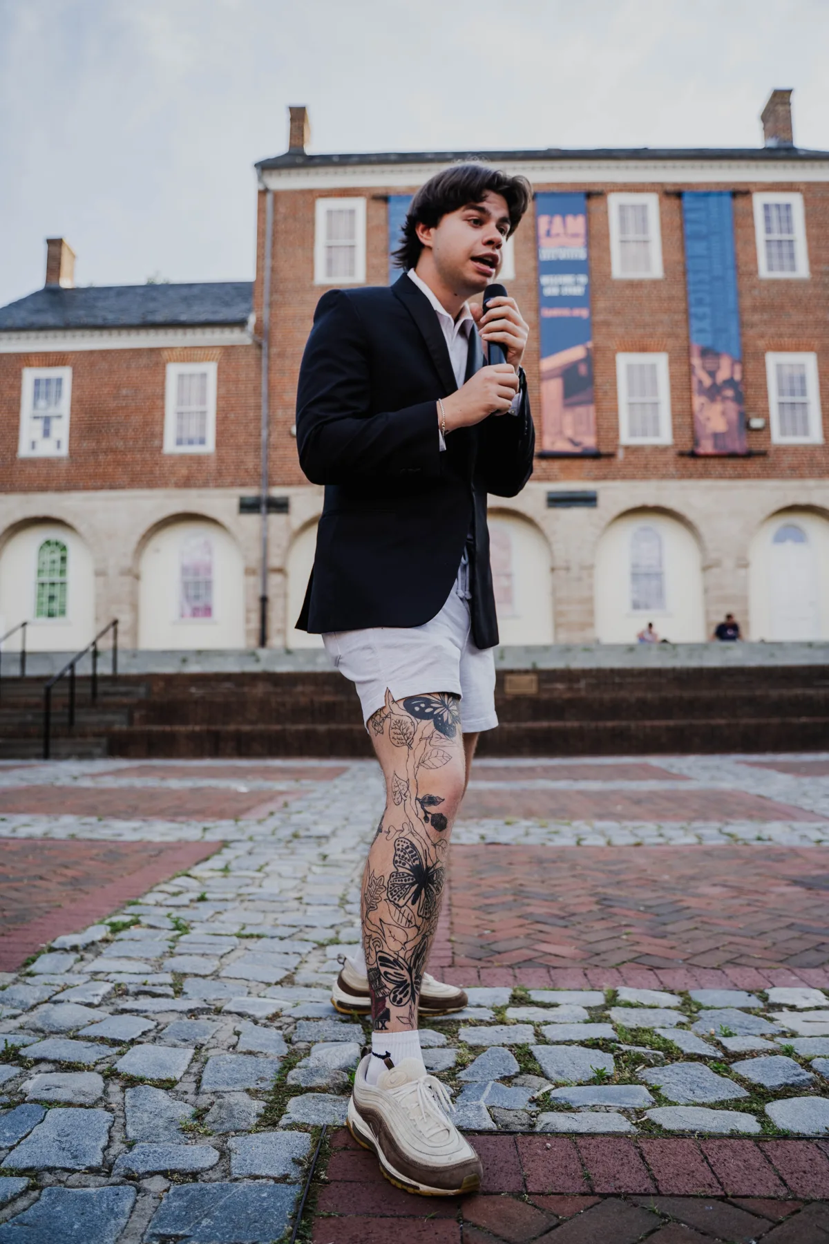 An Upchurch emcee on the mic in front of a brick courthouse venue.