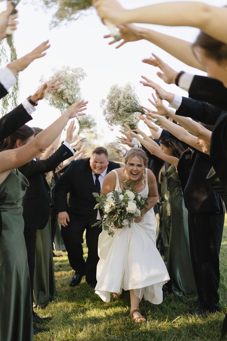 A bride twirling through a tunnel of cheering guests at her wedding send-off.